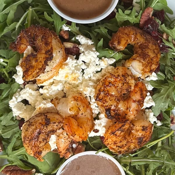 Arugula salad with grilled shrimp, feta cheese, pecans, dried cranberries, and two cups of dressing.