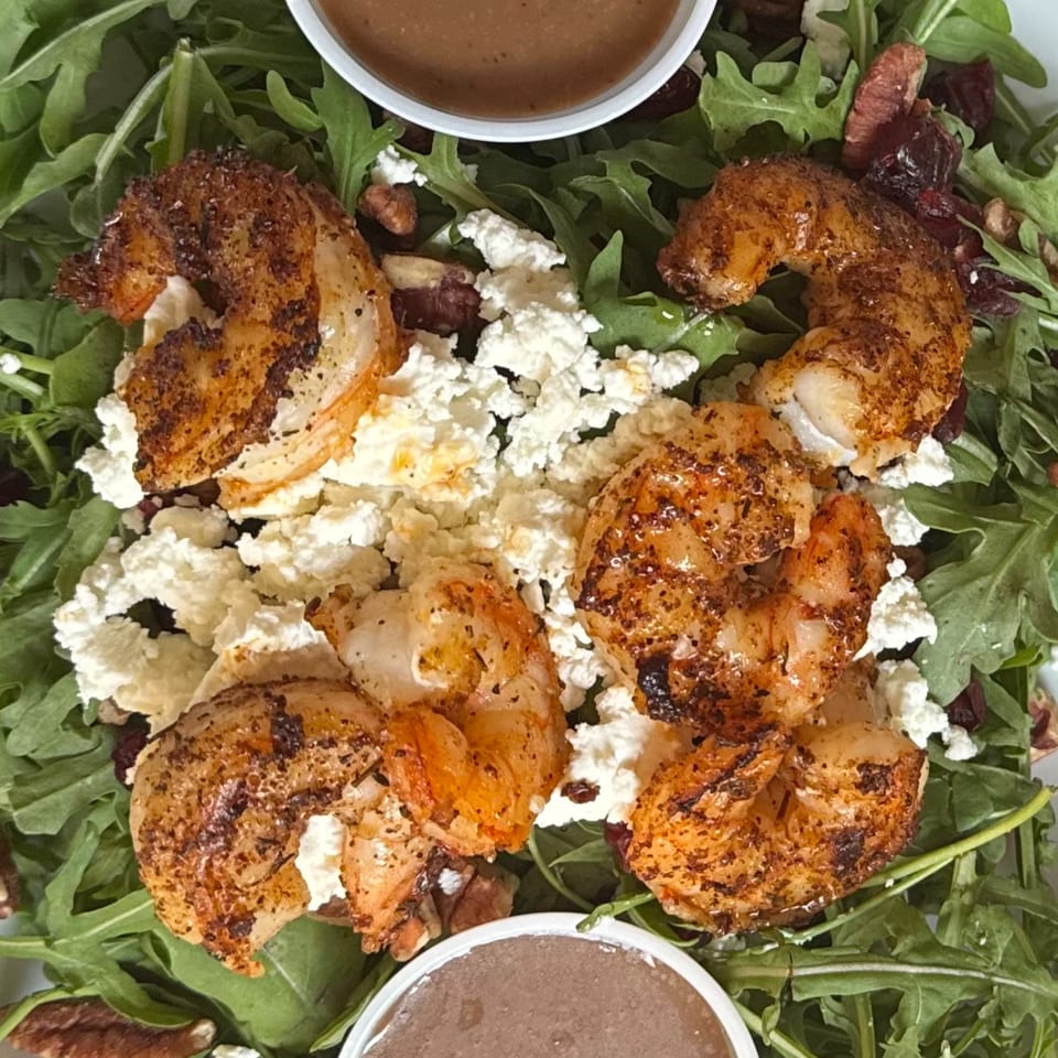 Arugula salad with grilled shrimp, feta cheese, pecans, dried cranberries, and two cups of dressing.