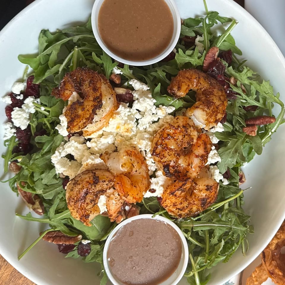 Arugula salad with grilled shrimp, feta cheese, pecans, dried cranberries, and two cups of dressing.